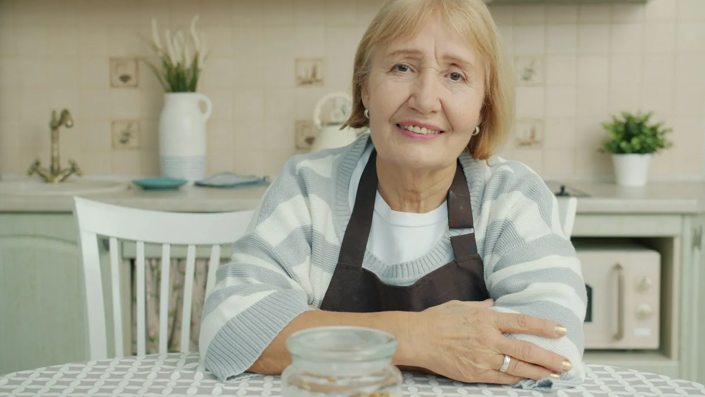 Idosa sorridente na cozinha de casa, ilustrando cuidados com a constipação em idosos